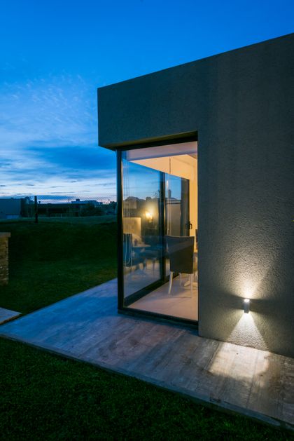Fachada moderna con ventanales de piso a techo al atardecer — proyecto Costa Esmeralda 3, por Arquitecto Caceres, en Costa Esmeralda