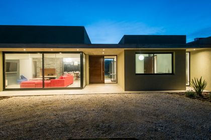 Fachada moderna con grandes ventanales e iluminación cálida — proyecto Costa Esmeralda 3, por Arquitecto Caceres, en Costa Esmeralda