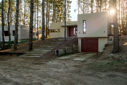 Casa moderna de hormigón y madera en bosque con grandes ventanales — proyecto Costa Esmeralda Casa MAI Lote 374 Deportiva, por Arquitecto Caceres, en Costa Esmeralda