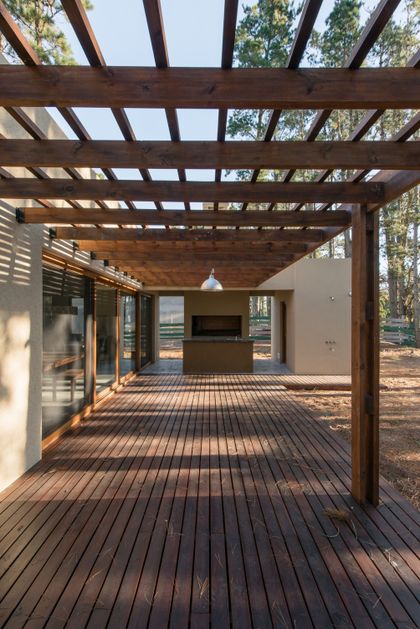Terraza de madera con pérgola y parrilla exterior — proyecto Costa Esmeralda Casa MAI Lote 374 Deportiva, por Arquitecto Caceres, en Costa Esmeralda