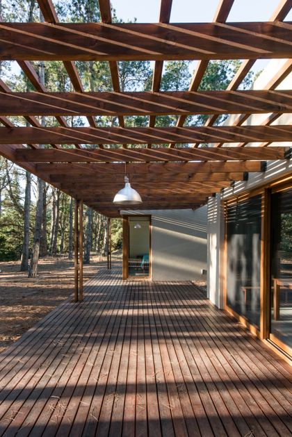 Terraza de madera y pérgola de madera en entorno de bosque — proyecto Costa Esmeralda Casa MAI Lote 374 Deportiva, por Arquitecto Caceres, en Costa Esmeralda