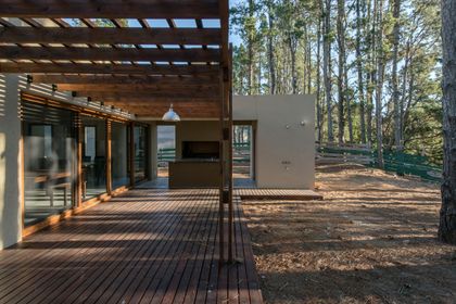 fachada moderna con pérgola de madera y deck en bosque — proyecto Costa Esmeralda Casa MAI Lote 374 Deportiva, por Arquitecto Caceres, en Costa Esmeralda