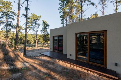 Casa moderna con fachada de estuco y madera en bosque — proyecto Costa Esmeralda Casa MAI Lote 374 Deportiva, por Arquitecto Caceres, en Costa Esmeralda