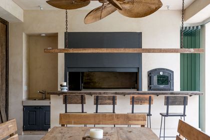 Quincho rústico industrial con gran ventilador de techo y muebles de madera — proyecto Aires Orientales, por Ricardo Pereyra Iraola 