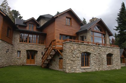 Fachada rústica de piedra y madera en montaña — proyecto Corrientes del Nahuel, por Ricardo Pereyra Iraola , en Bariloche