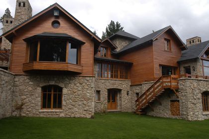 fachada de casa rústica con piedra y madera — proyecto Corrientes del Nahuel, por Ricardo Pereyra Iraola , en Bariloche