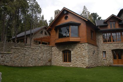 Fachada rústica de piedra y madera en entorno boscoso — proyecto Corrientes del Nahuel, por Ricardo Pereyra Iraola , en Bariloche