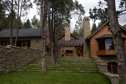 Fachada rústica de piedra con escaleras en terraza y montaña — proyecto Corrientes del Nahuel, por Ricardo Pereyra Iraola , en Bariloche