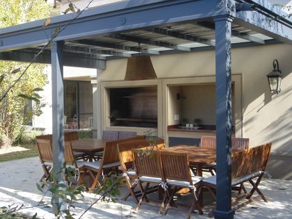 Área de parrilla exterior moderna con pergola y comedor — proyecto Elegante Equilibrio, por Ricardo Pereyra Iraola 