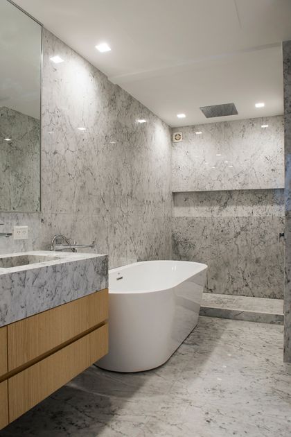 Baño moderno con revestimiento de mármol gris y bañera exenta — proyecto Lafinur, por Estudio Magrane, en CABA