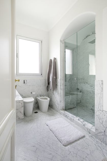 Baño moderno con paredes y pisos de mármol blanco — proyecto Libertador y Salguero, por Estudio Magrane, en CABA