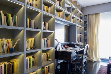 Biblioteca iluminada y escritorio con silla de oficina junto a ventanal — proyecto Libertador y Lafinur, por Estudio Magrane, en CABA