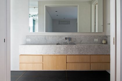 Baño moderno con mesada de mármol gris y mueble de madera — proyecto Los Patricios, por Estudio Magrane