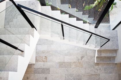 Escalera de mármol gris con baranda de hierro negro y vidrio — proyecto Los Patricios, por Estudio Magrane