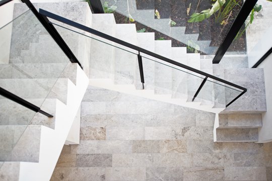 Escalera de mármol gris con baranda de hierro negro y vidrio — proyecto Los Patricios, por Estudio Magrane
