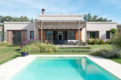 Pileta rectangular moderna con pérgola de madera y vista a la casa — proyecto Santa María de Lobos, por Estudio Magrane, en Lobos