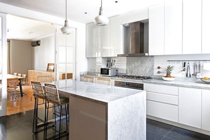 Cocina moderna con isla central, mesada de mármol y ventanal al comedor — proyecto Vicente Lopez, por Estudio Magrane, en Vicente López