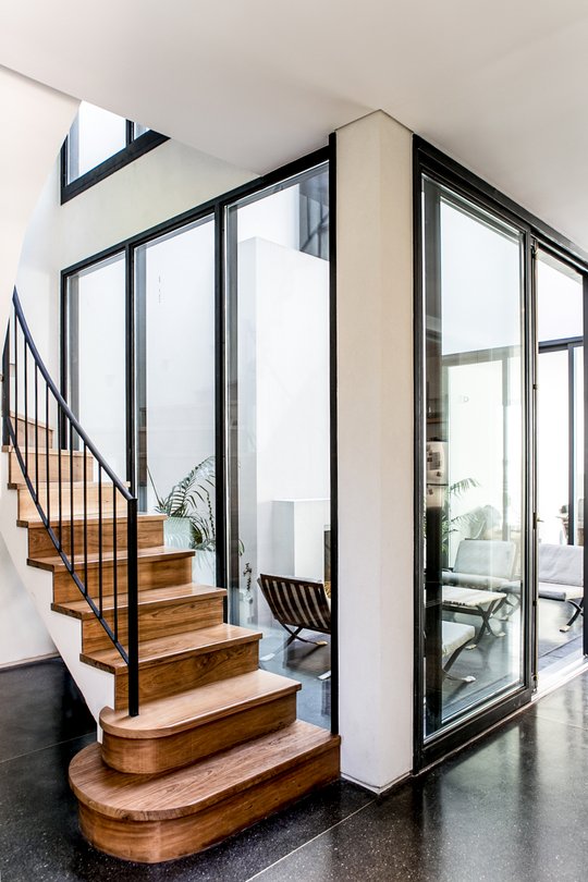 escalera de madera con baranda de hierro negro junto a ventanales — proyecto Belgrano, por Estudio Magrane, en Belgrano