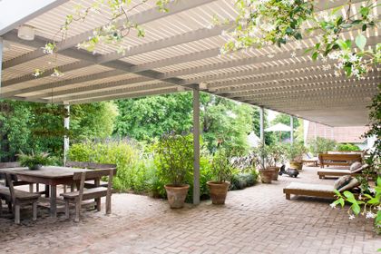galería exterior con techo de pérgola y comedor de madera — proyecto Pilar, por Estudio Magrane, en Pilar