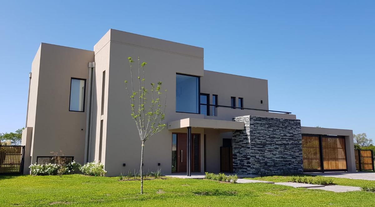 Fachada moderna com paredes de concreto e pedra, e amplas janelas — projeto HARAS SANTA MARIA, por Ramirez Arquitectura, em Escobar