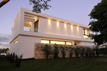 Fachada moderna con piedra y luces integradas — proyecto CASA GOLF, por Ramirez Arquitectura, en Nordelta