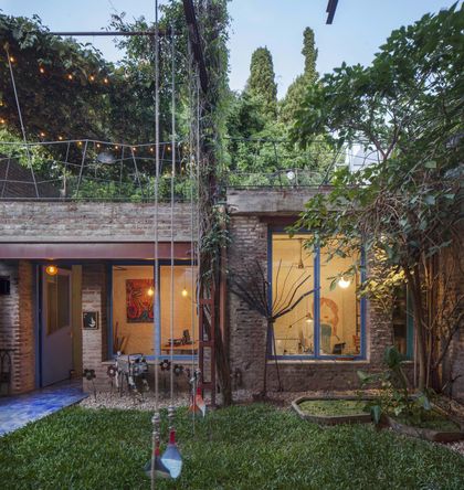 fachada moderna con ladrillo expuesto y vegetación exuberante — proyecto Casa Warnes, por Silvia Soqueff, en CABA
