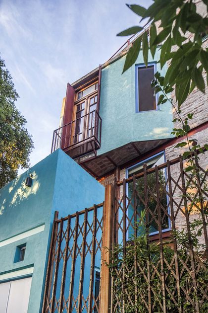 Fachada moderna azul y ladrillo con reja metálica plegable — proyecto Casa Warnes, por Silvia Soqueff, en CABA