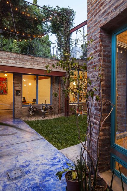 Patio moderno con piso de hormigón azul y ladrillos expuestos — proyecto Casa Warnes, por Silvia Soqueff, en CABA
