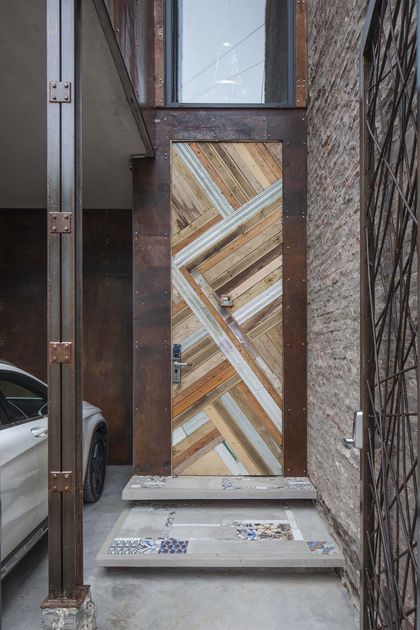 puerta geométrica de madera y metal en fachada industrial con escalones de mosaico — proyecto Casa Lavalle, por Silvia Soqueff, en CABA