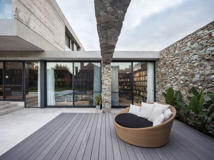 Patio moderno con sofá circular de ratán y muros de hormigón y piedra — proyecto CASA GÜELL, por OON ARCHITECTURE