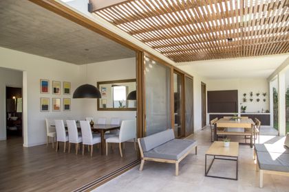 Comedor y sala semi-cubiertos con techo de madera y grandes ventanales — proyecto LS 624, por Grupo Pauta Arquitectura