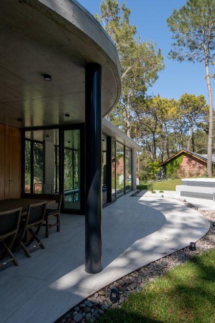 Arquitectura moderna con muros curvos de hormigón y vistas al bosque — proyecto Casa G y G, por TAVA Coop, en Cariló