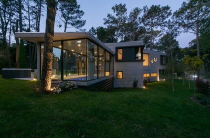 fachada moderna con ventanales y entorno boscoso — proyecto Casa G y G, por TAVA Coop, en Cariló