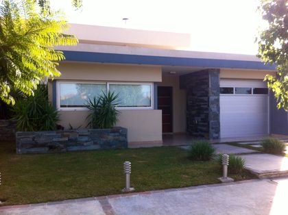 Fachada moderna con ventanas amplias y detalles en piedra y metal — proyecto Jardin Claret M, por Blussand Tosco, en Córdoba