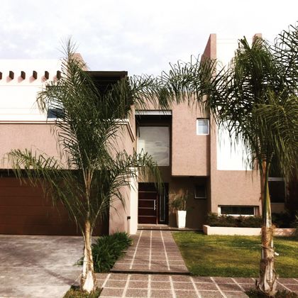 Fachada moderna con palmeras y ventanales — proyecto Jardin Claret M, por Blussand Tosco, en Córdoba