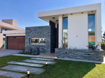 Fachada moderna con contraste de piedra, concreto y vidrio — proyecto Manantiales Z, por Blussand Tosco, en Córdoba