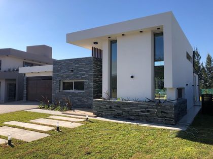 Fachada moderna de casa con detalles en piedra y amplios ventanales — proyecto Manantiales Z, por Blussand Tosco, en Córdoba