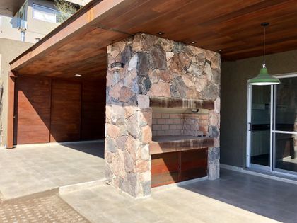 Amplio quincho moderno con parrilla de piedra y techo de madera — proyecto Q2 PC, por Blussand Tosco