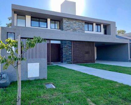 Fachada moderna con paneles de madera y ventanales amplios — proyecto Santina Norte, por Blussand Tosco, en Córdoba