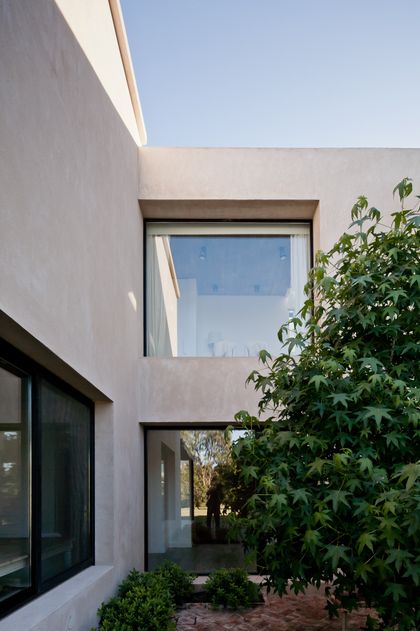 Fachada minimalista blanca con ventanales y enredadera lateral — proyecto La Tahona, por BAS Y GARCIA , en Canelones Departamento de Canelones