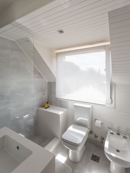 Baño minimalista blanco con bañera, inodoro y ventanal luminoso — proyecto The Classic, por BAS Y GARCIA , en San Isidro