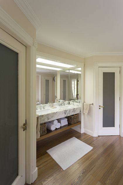 Baño moderno con mesada de mármol y espejo grande iluminado — proyecto The Classic, por BAS Y GARCIA , en San Isidro