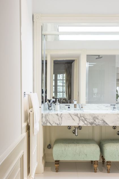 Baño minimalista con mesada de mármol, espejo grande y banquetas verdes — proyecto The Classic, por BAS Y GARCIA , en San Isidro
