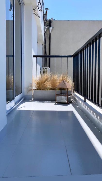 Terraza minimalista con plantas ornamentales y vista urbana — proyecto Melo, por Biaus Pieres Arquitectura, en CABA