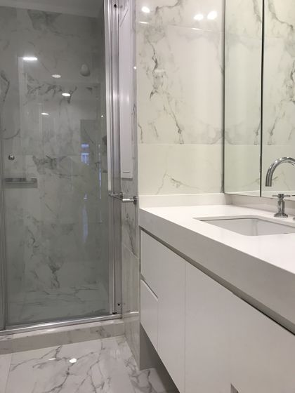 Baño moderno con marmol, ducha cristal y mesada blanca minimalista — proyecto Paraná , por Biaus Pieres Arquitectura, en CABA