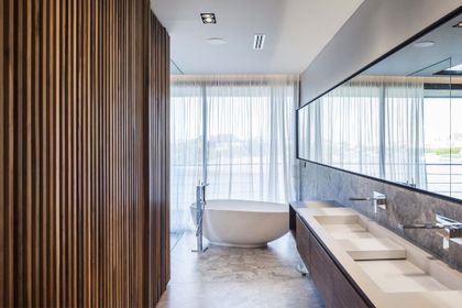 baño moderno con bañera, mesadas marmol y ventanal con vistas — proyecto Casa India , por Estudio Simbiosis