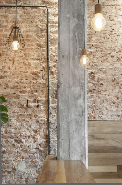 Pasillo con ladrillo visto y columna de hormigón, lámparas colgantes industriales — proyecto Estilo Barista, por Estudio Simbiosis