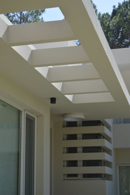 Fachada moderna con pérgola geométrica y luz natural — proyecto PINAMAR NORTE, por LADAGA-RUARTE-Pinamar, en Pinamar