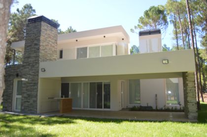 Fachada de casa moderna con volúmenes geométricos y materiales contrastantes — proyecto PINAMAR NORTE, por LADAGA-RUARTE-Pinamar, en Pinamar
