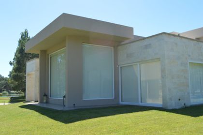 Fachada moderna con grandes ventanales y muros de piedra — proyecto LA HERRADURA - Boulevard III, por LADAGA-RUARTE-Pinamar, en Pinamar